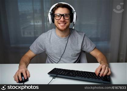 technology, gaming, entertainment, let&amp;#39;s play and people concept - happy smiling young man in eyeglasses with headset playing computer game at home and streaming playthrough or walkthrough video