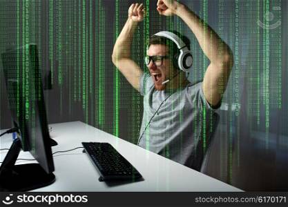 technology, gaming, entertainment, let&amp;#39;s play and people concept - happy young man in eyeglasses with headset playing and winning computer game at home and streaming playthrough or walkthrough video
