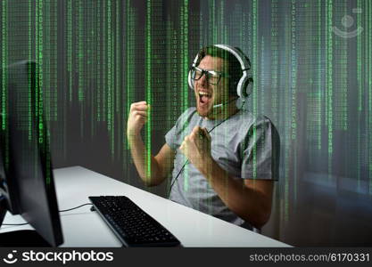 technology, gaming, entertainment, let&amp;#39;s play and people concept - happy young man in eyeglasses with headset playing and winning computer game at home and streaming playthrough or walkthrough video