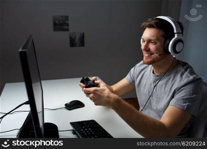 technology, gaming, entertainment, let&amp;#39;s play and people concept - happy young man in headset with controller gamepad playing computer game at home and streaming playthrough or walkthrough video