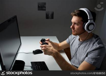 technology, gaming, entertainment, let&amp;#39;s play and people concept - young man in headset with controller gamepad playing computer game at home and streaming playthrough or walkthrough video