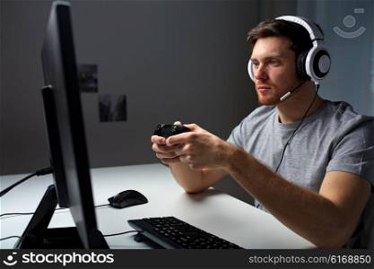 technology, gaming, entertainment, let&amp;#39;s play and people concept - young man in headset with controller gamepad playing computer game at home and streaming playthrough or walkthrough video