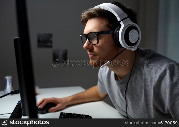 technology, gaming, entertainment, let&amp;#39;s play and people concept - young man in headset and glasses with pc computer playing game at home and streaming playthrough or walkthrough video