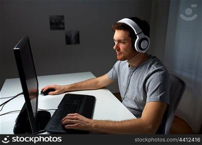 technology, gaming, entertainment, let&rsquo;s play and people concept - young man in headset with pc computer playing game at home and streaming playthrough or walkthrough video