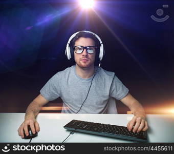 technology, gaming, entertainment, let&rsquo;s play and people concept - young man in headset and eyeglasses with pc computer playing game and streaming playthrough or walkthrough video over light