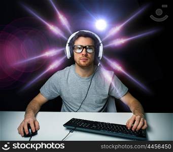 technology, gaming, entertainment, let&rsquo;s play and people concept - young man in headset and eyeglasses with pc computer playing game and streaming playthrough or walkthrough video over light