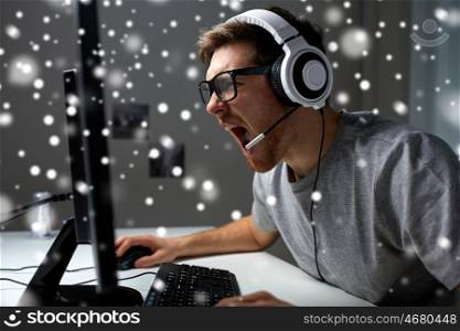 technology, gaming, entertainment, let's play and people concept - angry screaming young man in headset with pc computer playing game at home and streaming playthrough or walkthrough video over snow
