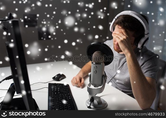 technology, gaming, entertainment, let's play and people concept - close up of sad young man in headset with pc computer playing game at home and streaming playthrough or walkthrough video over snow