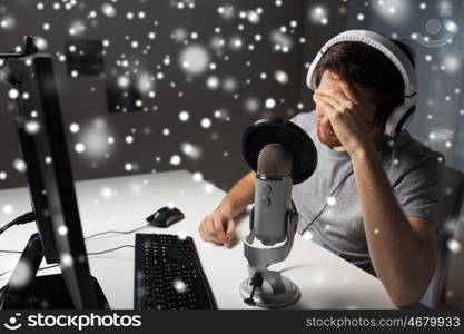 technology, gaming, entertainment, let's play and people concept - close up of sad young man in headset with pc computer playing game at home and streaming playthrough or walkthrough video over snow