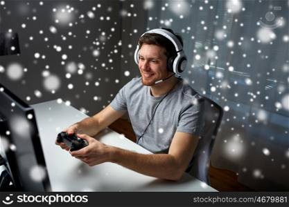 technology, gaming, entertainment, let's play and people concept - happy man in headset with controller gamepad playing computer game at home and streaming playthrough or walkthrough video over snow