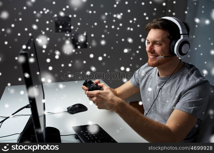 technology, gaming, entertainment, let's play and people concept - happy man in headset with controller gamepad playing computer game at home and streaming playthrough or walkthrough video over snow