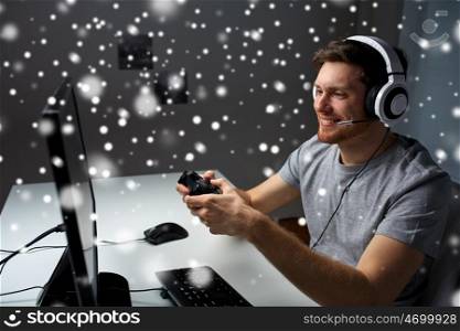 technology, gaming, entertainment, let's play and people concept - happy man in headset with controller gamepad playing computer game at home and streaming playthrough or walkthrough video over snow