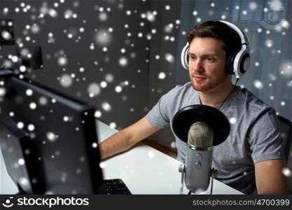 technology, gaming, entertainment, let's play and people concept - happy young man in headset with pc computer playing game at home and streaming playthrough or walkthrough video over snow