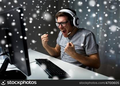 technology, gaming, entertainment, let's play and people concept - man in eyeglasses with headset playing and winning computer game at home and streaming playthrough or walkthrough video over snow