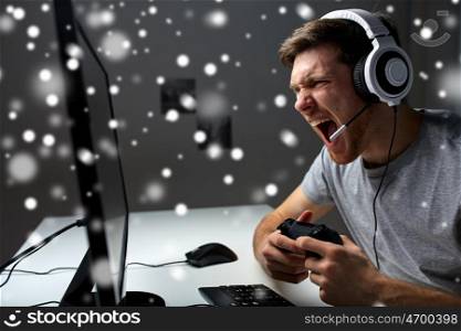 technology, gaming, entertainment, let's play and people concept - screaming man in headset with controller gamepad playing computer game at home and streaming playthrough walkthrough video over snow