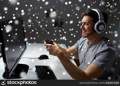 technology, gaming, entertainment, let's play and people concept - young man in headset with controller gamepad playing computer game at home and streaming playthrough or walkthrough video over snow