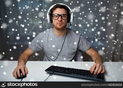 technology, gaming, entertainment, let's play and people concept - young man in headset and eyeglasses with pc computer playing game at home and streaming playthrough or walkthrough video over snow