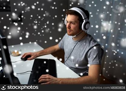 technology, gaming, entertainment, let's play and people concept - young man in headset with pc computer playing game at home and streaming playthrough or walkthrough video over snow