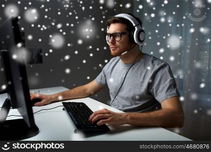 technology, gaming, entertainment, let's play and people concept - young man in headset and glasses with pc computer playing game at home and streaming playthrough or walkthrough video over snow