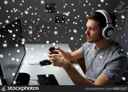 technology, gaming, entertainment, let's play and people concept - young man in headset with controller gamepad playing computer game at home and streaming playthrough or walkthrough video over snow