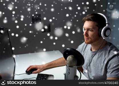 technology, gaming, entertainment, let's play and people concept - young man in headset with pc computer playing game at home and streaming playthrough or walkthrough video over snow
