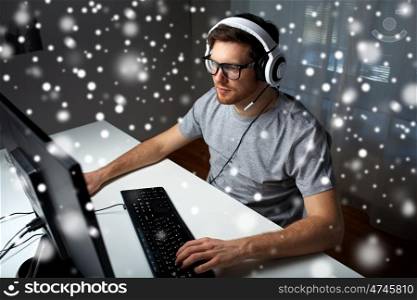 technology, gaming, entertainment, let's play and people concept - young man in headset and glasses with pc computer playing game at home and streaming playthrough or walkthrough video over snow