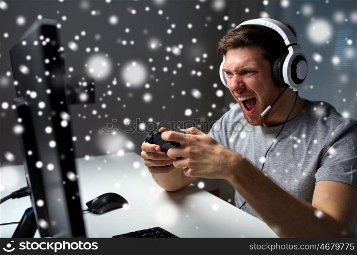 technology, gaming, entertainment, play and people concept - screaming young man in headset with controller gamepad playing computer game and streaming playthrough or walkthrough video over snow