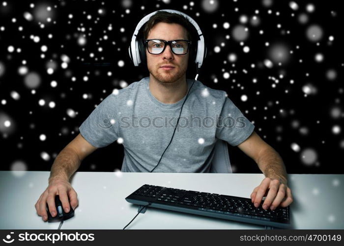 technology, gaming, let's play and people concept - man or hacker in headset and eyeglasses with pc computer playing game and streaming playthrough or walkthrough video over black background over snow