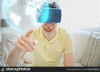 technology, global, international, gaming and people concept - happy young man in virtual reality headset or 3d glasses playing video game with earth or planet hologram at home