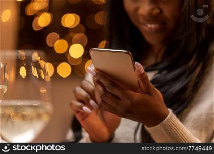 technology, holidays and celebration concept - close up of happy woman with smartphone at christmas dinner party. woman with smartphone at christmas dinner party