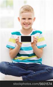 technology, home, advertising and childhood concept - little boy showing smartphone black blank screen at home