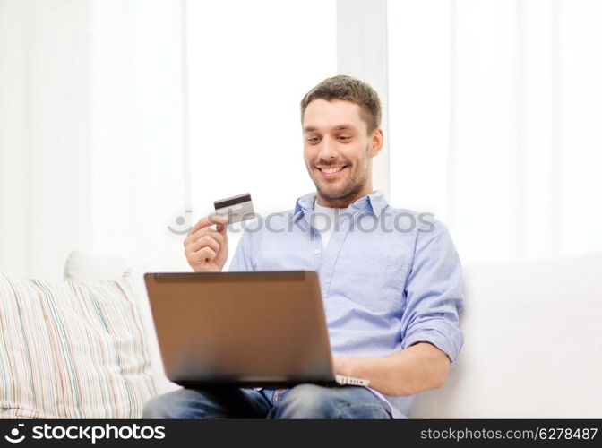 technology, home and lifestyle concept - smiling man working with laptop and credit card at home