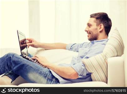 technology, home and lifestyle concept - smiling man working with laptop at home