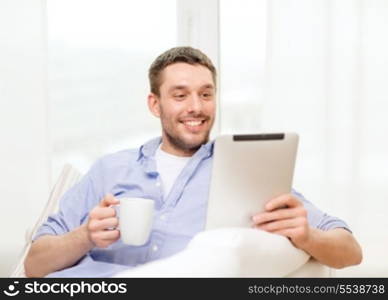 technology, home and lifestyle concept - smiling man working with tablet pc computer and coffee cup at home