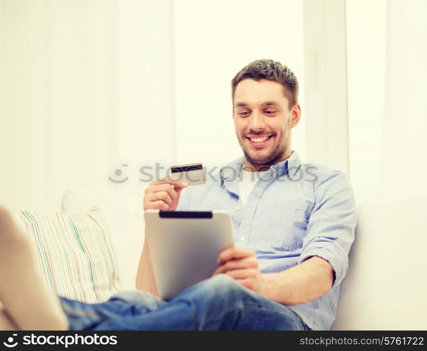 technology, home and lifestyle concept - smiling man working with tablet pc computer and credit card at home