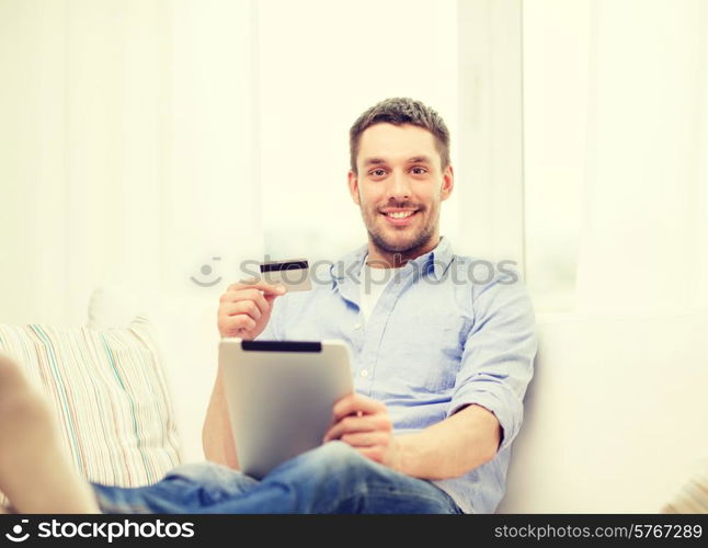 technology, home and lifestyle concept - smiling man working with tablet pc computer and credit card at home