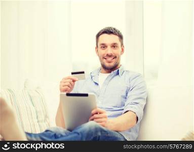 technology, home and lifestyle concept - smiling man working with tablet pc computer and credit card at home