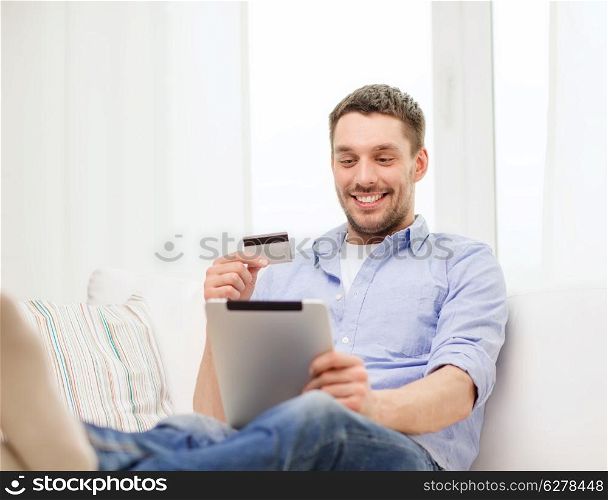 technology, home and lifestyle concept - smiling man working with tablet pc computer and credit card at home