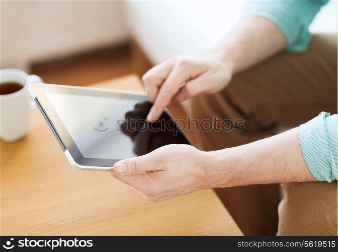 technology, home, drinks and lifestyle concept - close up of man with tablet pc computer and cup of coffee at home