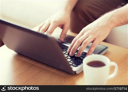 technology, home, drinks and lifestyle concept - close up of man with laptop and cup of coffee at home
