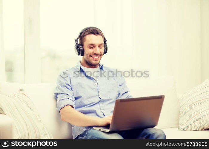 technology, home, music and lifestyle concept - smiling man with laptop and headphones at home