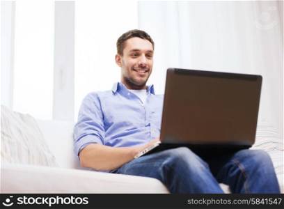 technology, home, people and lifestyle concept - smiling man working with laptop at home