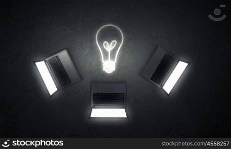 Technology idea. Three opened laptop computers and light bulb concept