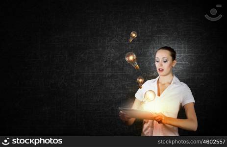 Technology in hands. Young businesswoman using tablet pc and light bulbs flying out