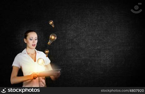 Technology in hands. Young businesswoman using tablet pc and light bulbs flying out