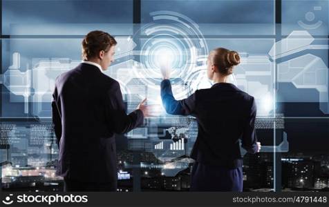 Technology innovations. Rear view of businessman and businesswoman touching icon of digital screen
