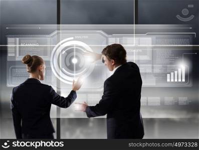 Technology innovations. Rear view of businessman and businesswoman touching icon of digital screen