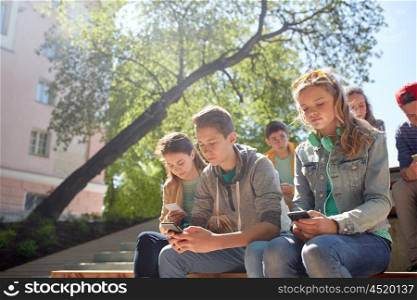technology, internet addiction and people concept - group of teenage friends or high school students with smartphones outdoors