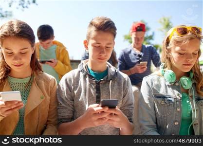technology, internet addiction and people concept - group of teenage friends or high school students with smartphones outdoors