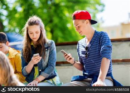 technology, internet addiction and people concept - happy teenage friends with smartphones outdoors